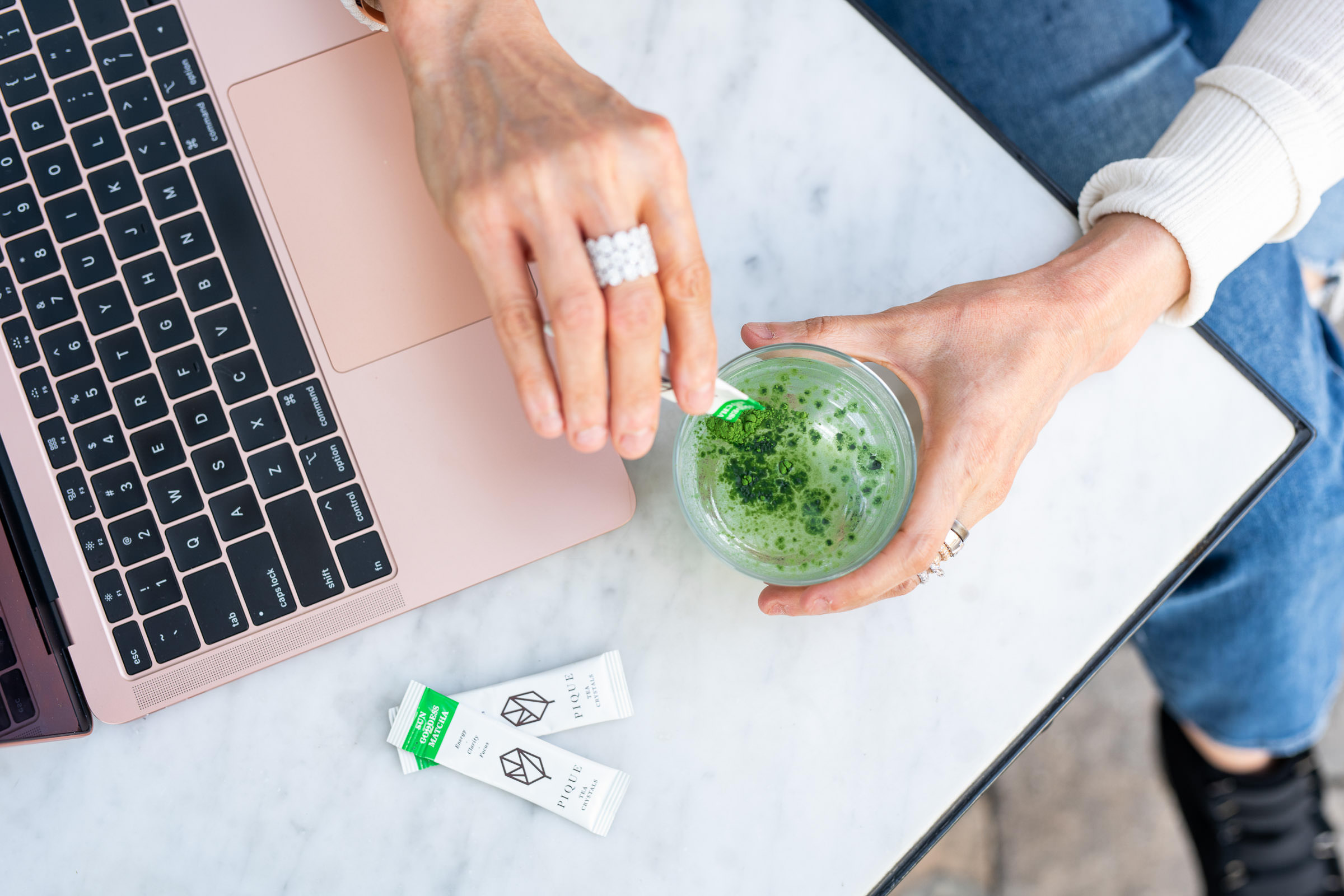 Hero Shot. Woman stirring a matcha drink next to her laptop for her brand photography photo shoot.