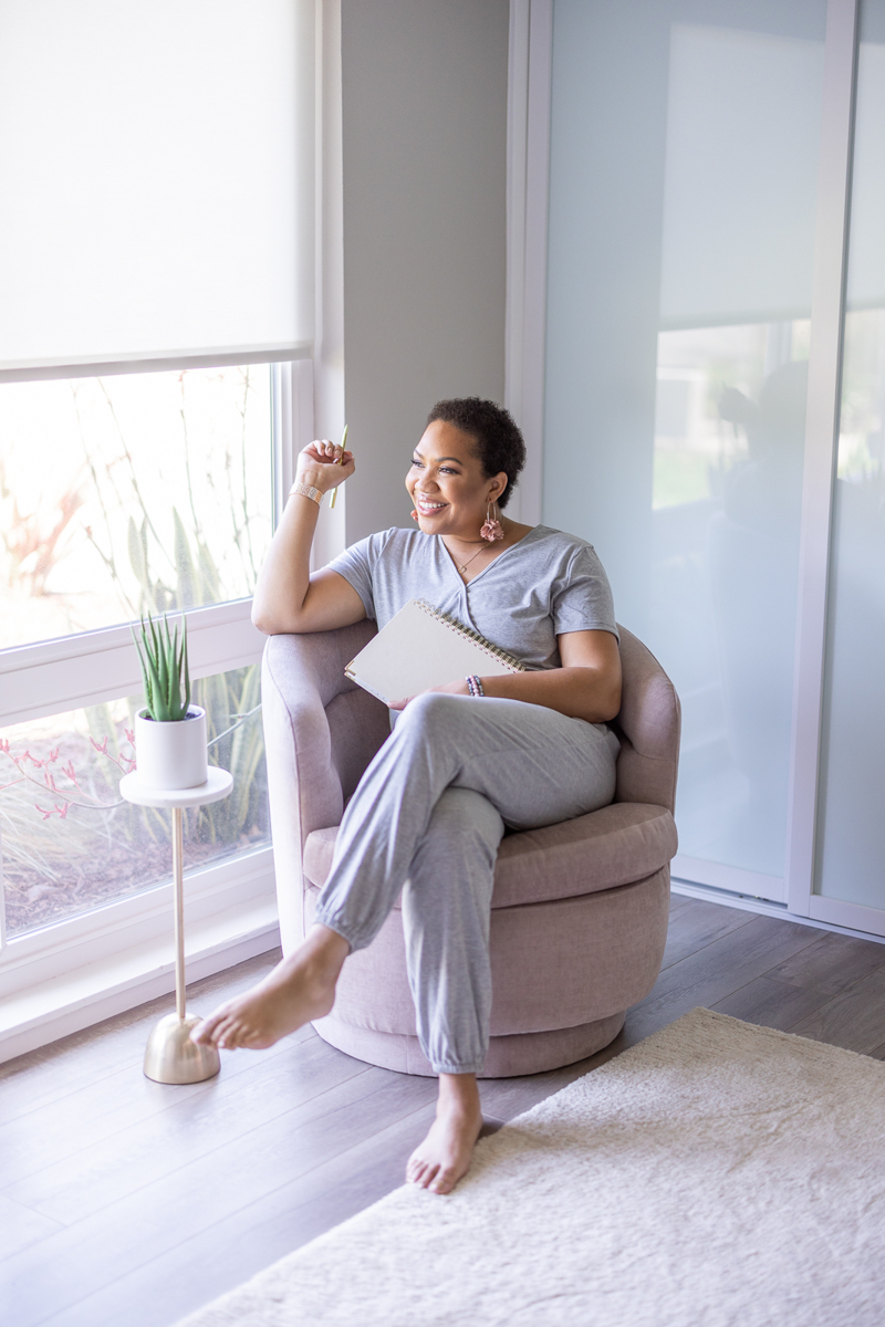 Woman sitting in a chair, dressed in loungewear and looking out the window.