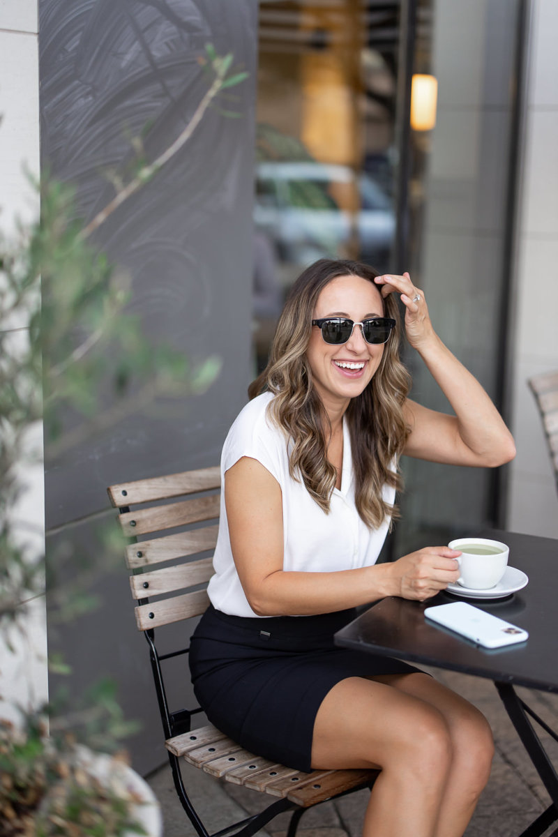  Woman drinking a hot beverage while sitting outside at a cafe.
