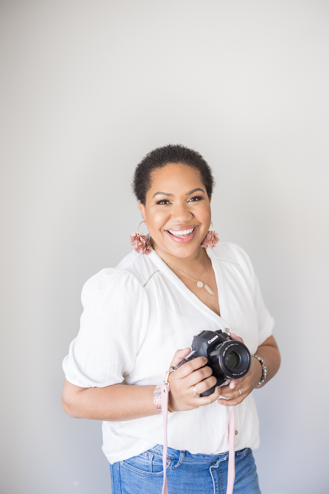 Woman holding a camera, and smiling during her branding photography session.

