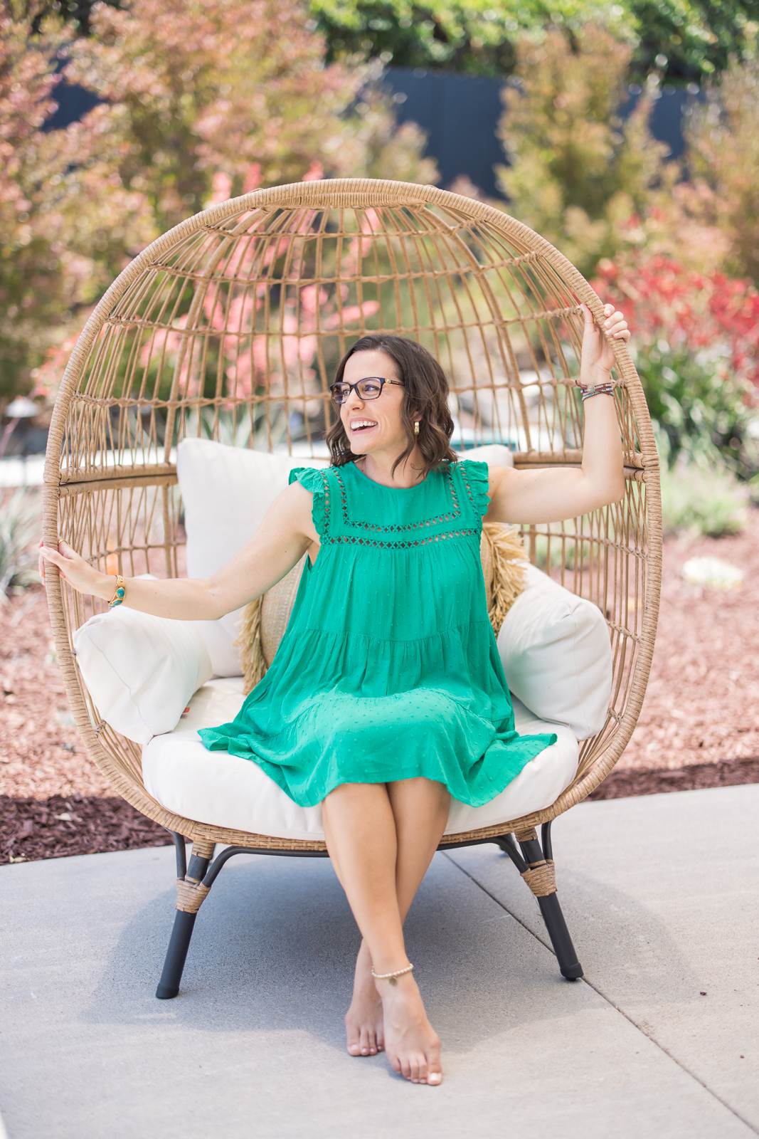 Woman wearing green, sitting in a big chair outside while looking away from Meg Marie during her personal brand photo shoot.
