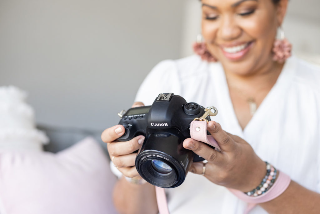 Woman holding camera with pink strap for her brand photos 