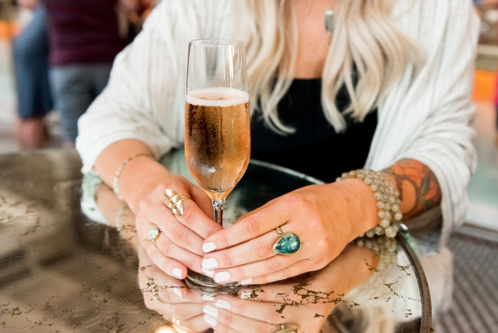 Woman holding a glass of champagne, wearing a mala bead bracelet during her spiritual entrepreneurship photo shoot. 
