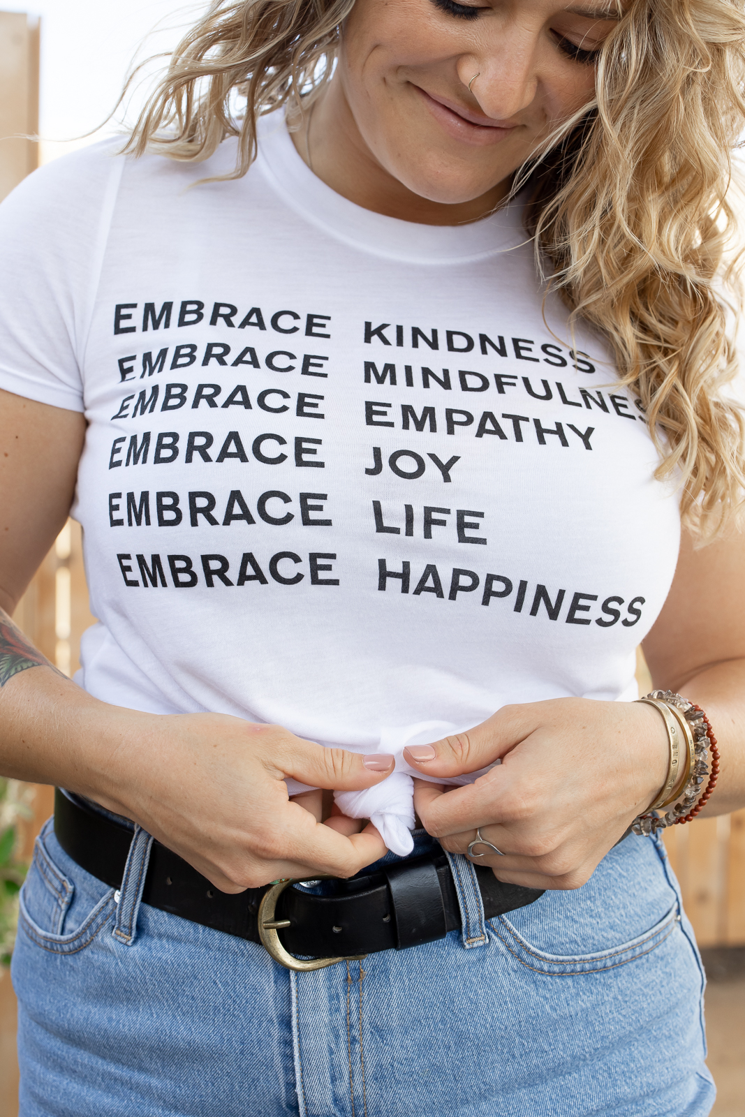 Woman wearing a white shirt with affirmations on it. 
