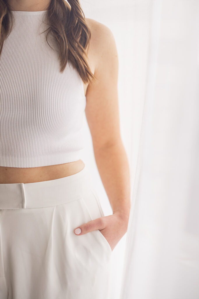 Close-up of a woman’s midsection with her hand in her pants pocket.