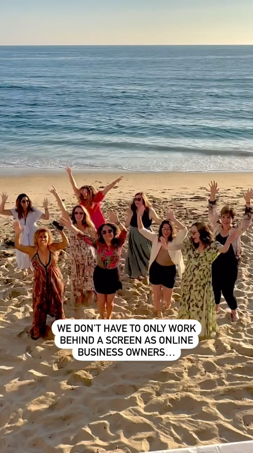 A group of women joyfully raise their arms on a sunny beach with a vast ocean view. Text reads: "We don't have to only work behind a screen as online business owners."