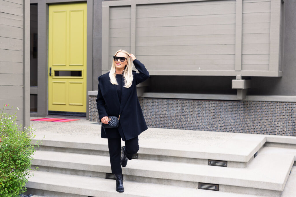 A woman in a black outfit and sunglasses stands confidently on modern gray steps, with a bright yellow door in the background. The scene feels stylish and contemporary. | Meg Marie Photography